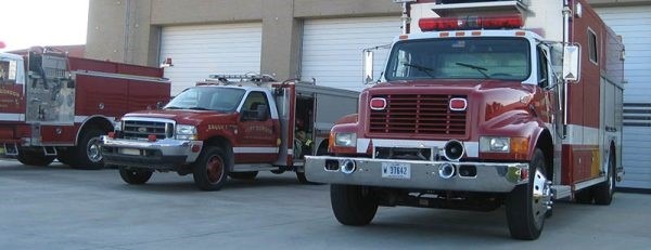 three fire trucks parked outside fire station