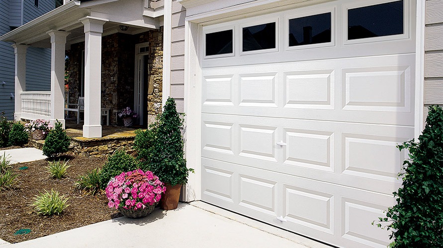 a white garage door sits in front of a house