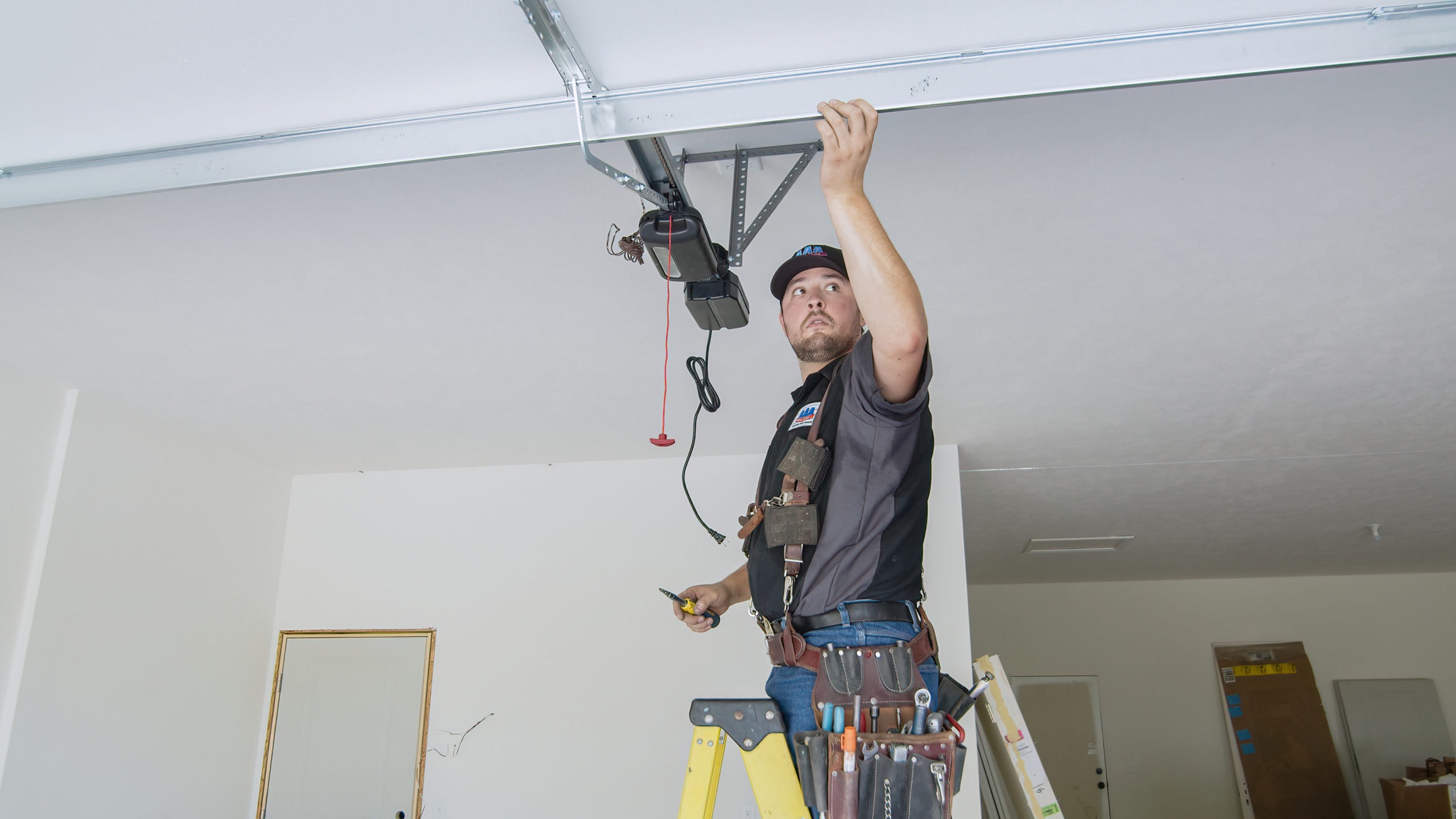 a man standing on a ladder working on a garage door