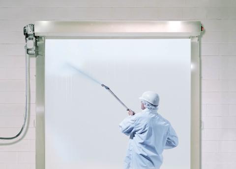 a man in a hazmat suit is cleaning a door with a sprayer